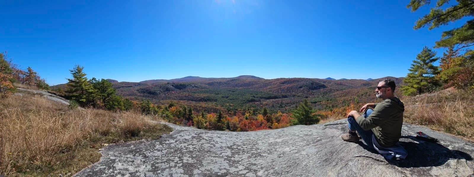 A hiker resting on a rock amid fall foliage